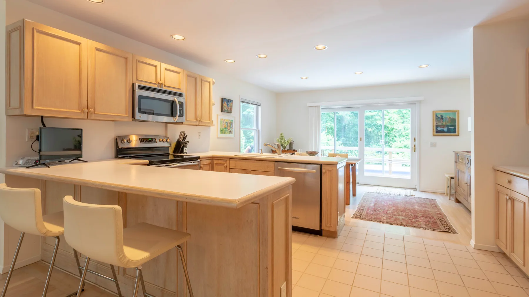 A bright kitchen with a central island and windows overlooking greenery.