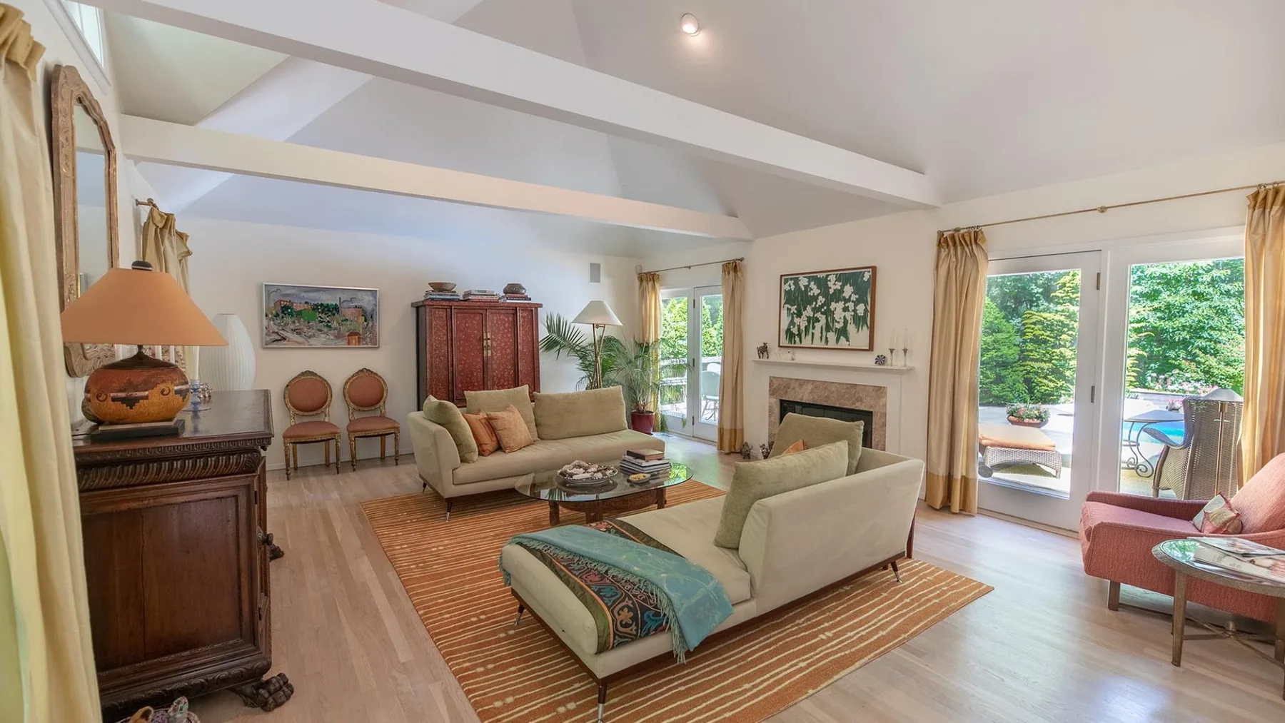 A bright living room with seating arranged around a coffee table and fireplace.