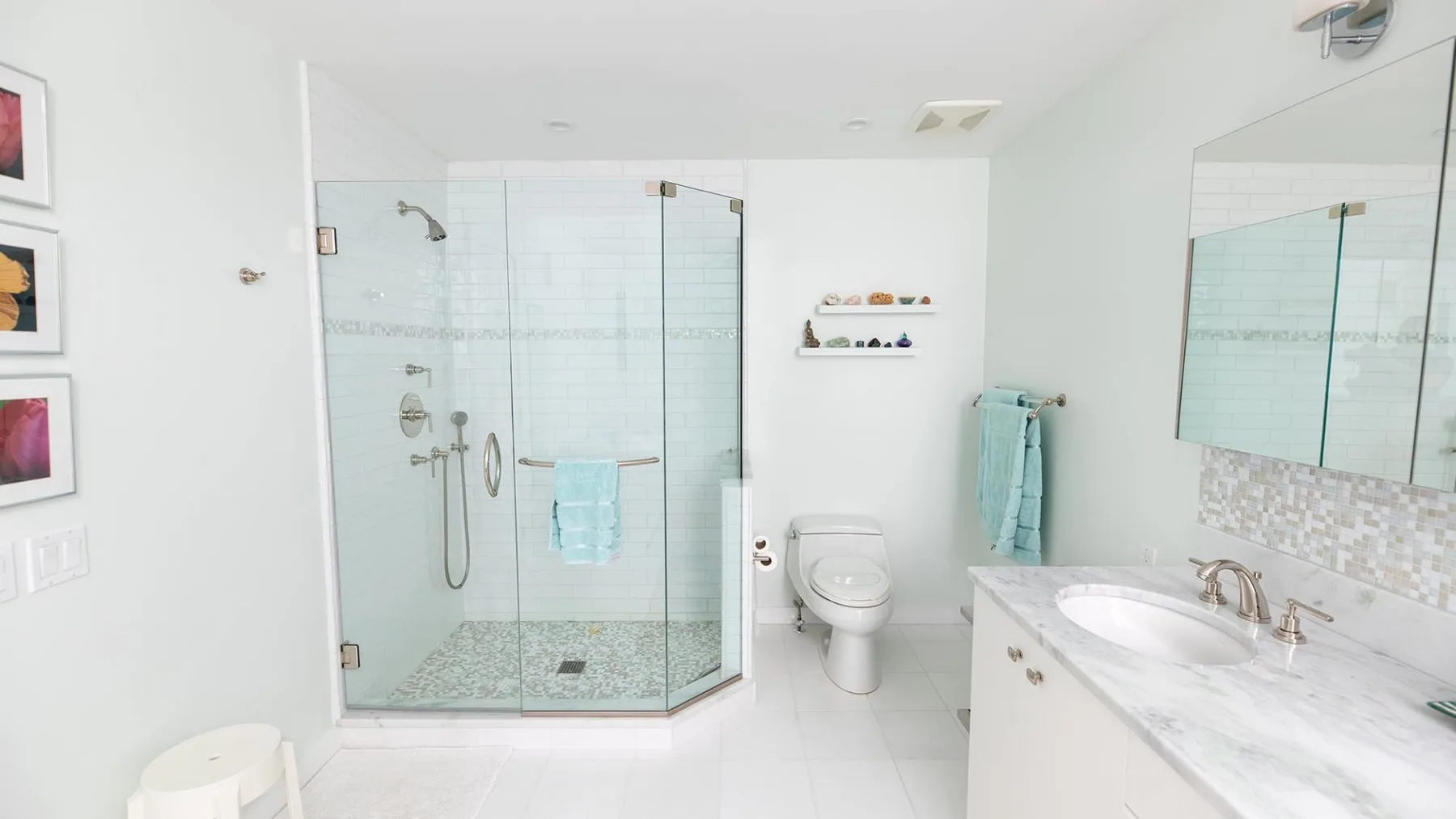 A bright bathroom with a glass shower, toilet, and long vanity.