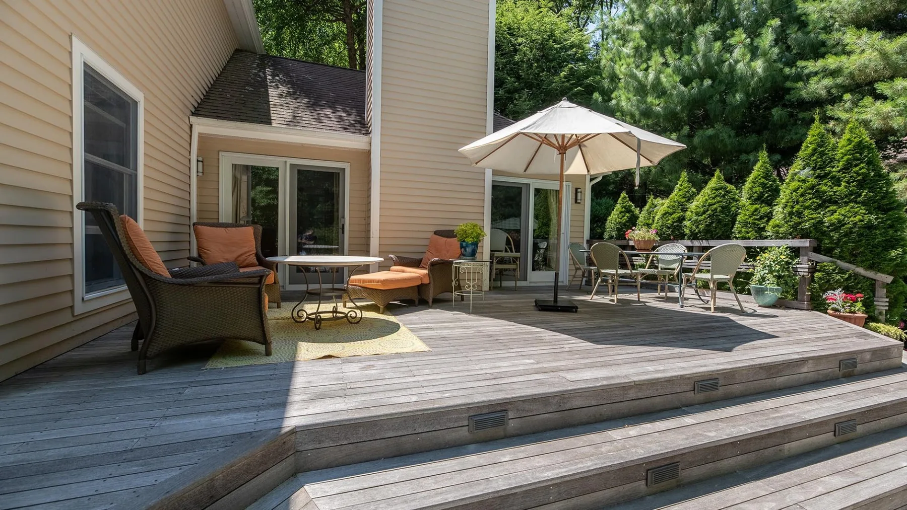 An outdoor deck with seating, a table, and a large patio umbrella.