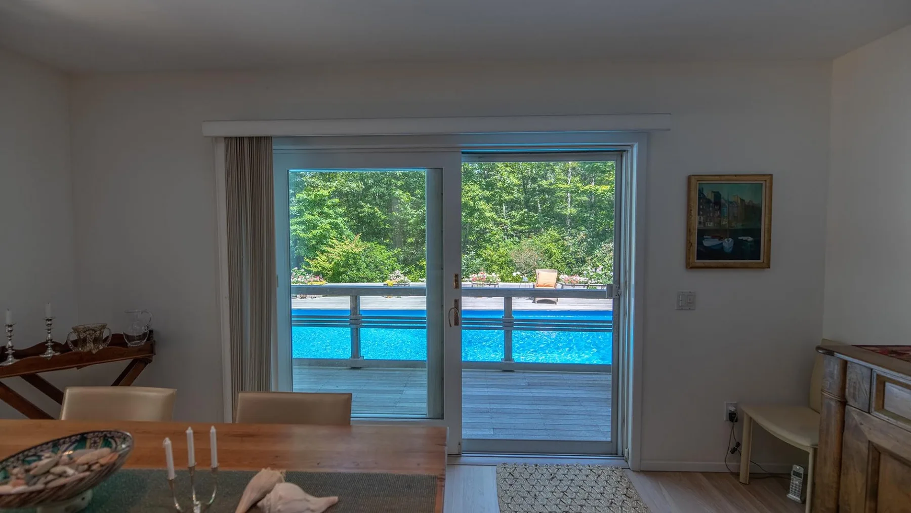 A dining area opens onto a patio with a bright blue swimming pool.