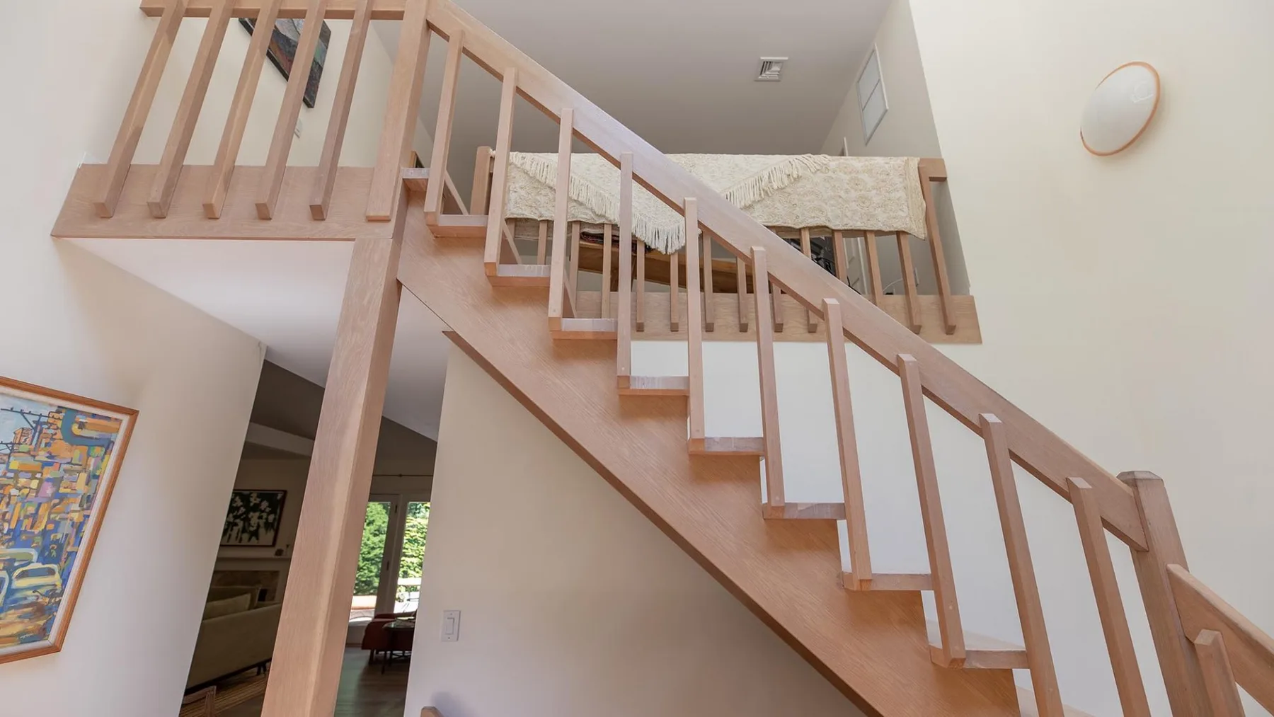 An indoor staircase with wooden railings leads to an upper landing.