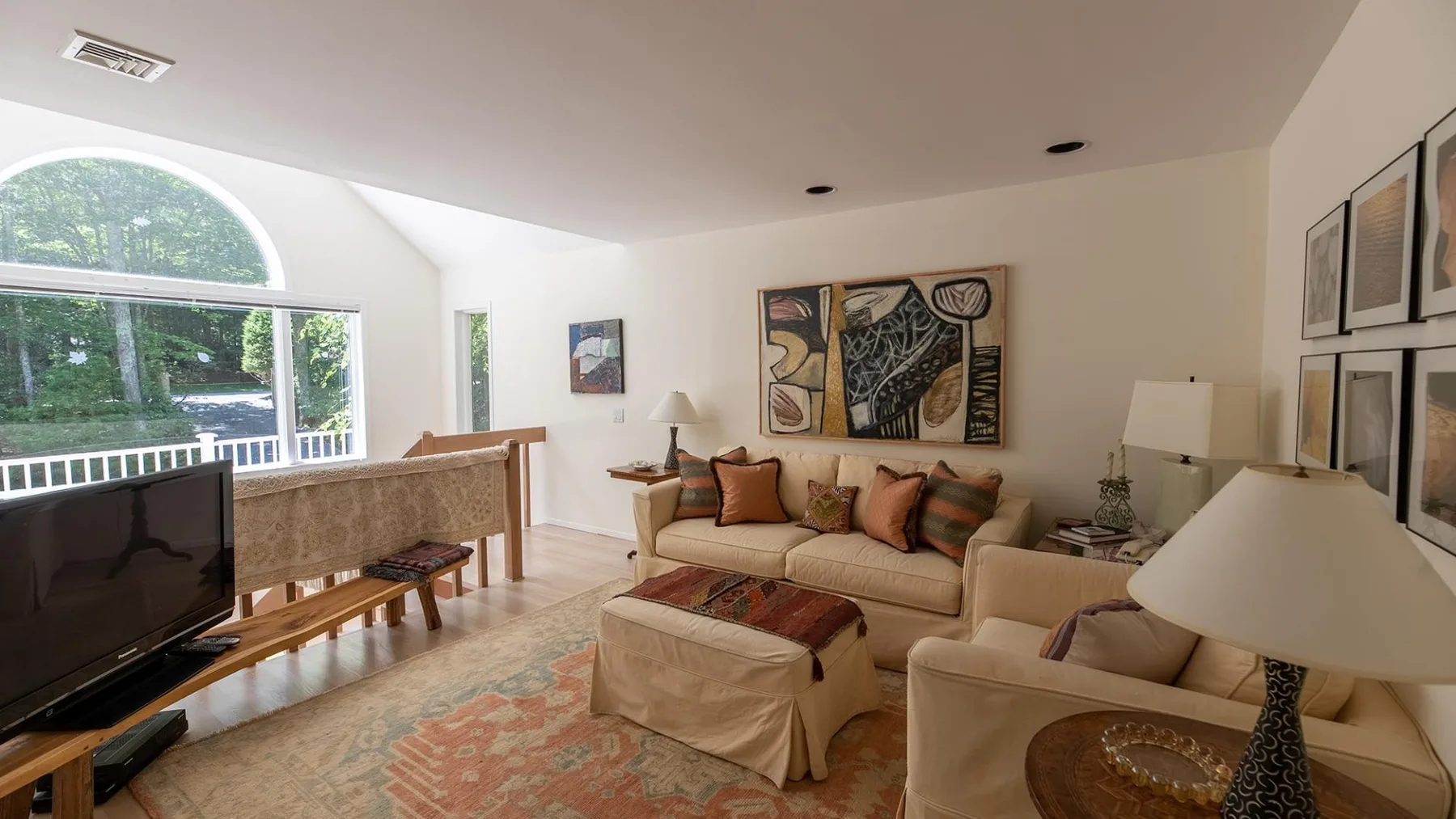 A bright living room with seating, a television, and large windows.