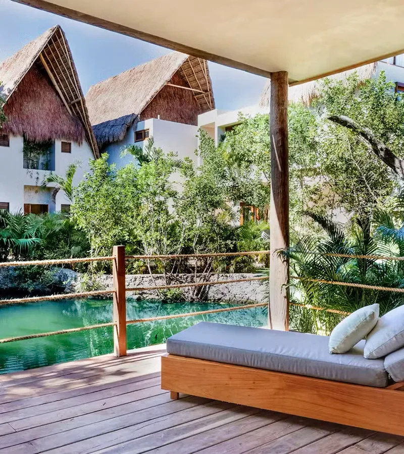 Outdoor bed on a wooden deck surrounded by jungle.
