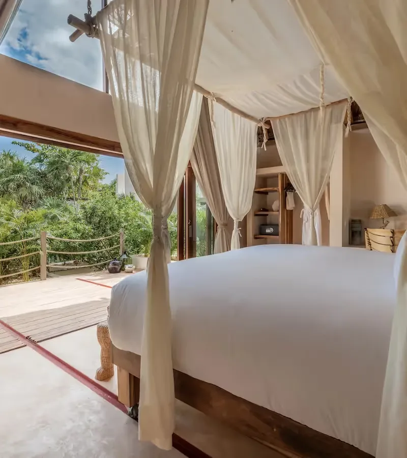 Hotel room with canopy bed and jungle view.