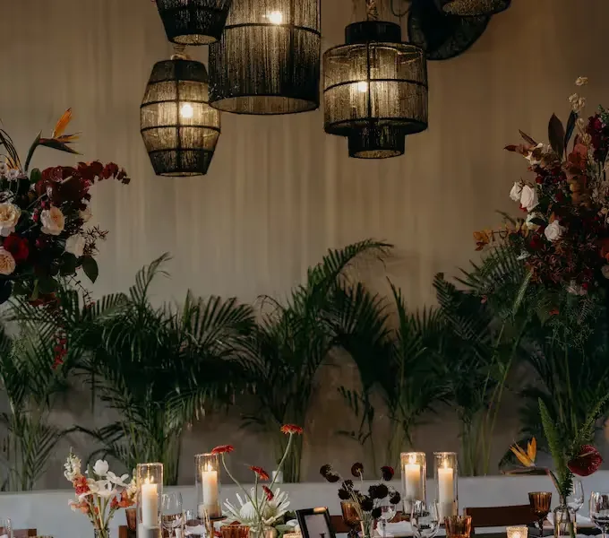 Dinner setting with lanterns and tropical floral arrangements.