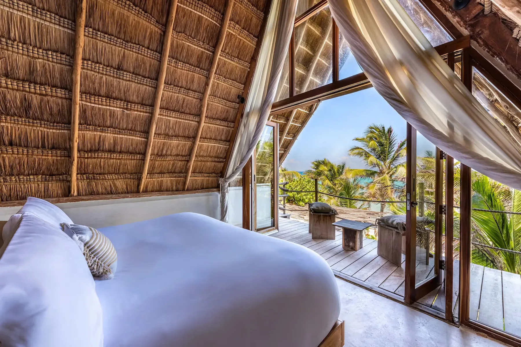 Beachfront suite with canopy bed and private ocean deck.