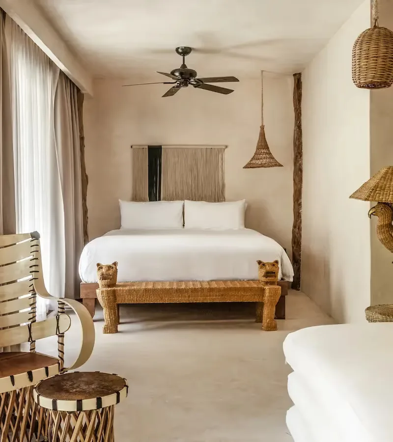 Suite with king-size bed, woven armchair, and rattan lighting.