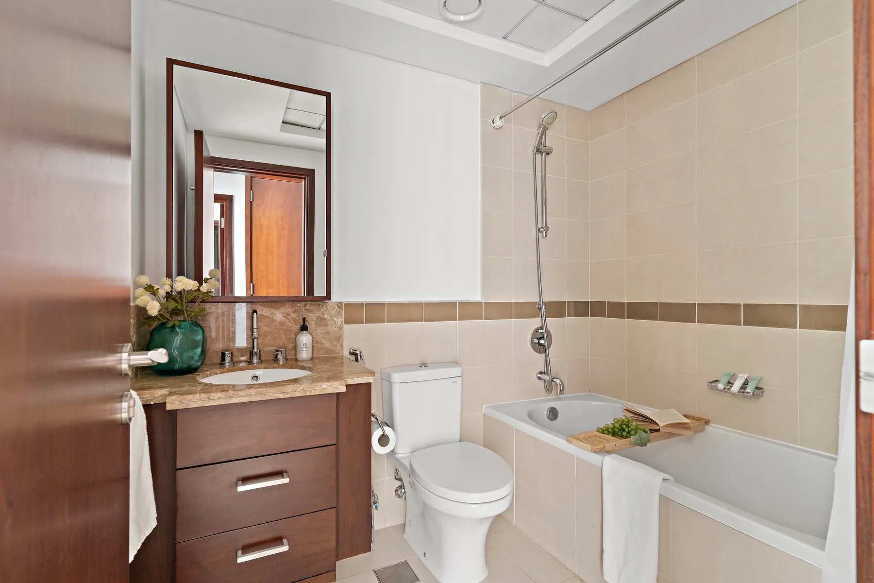 Un baño con lavabo, inodoro y bañera bajo una ducha montada en la pared.