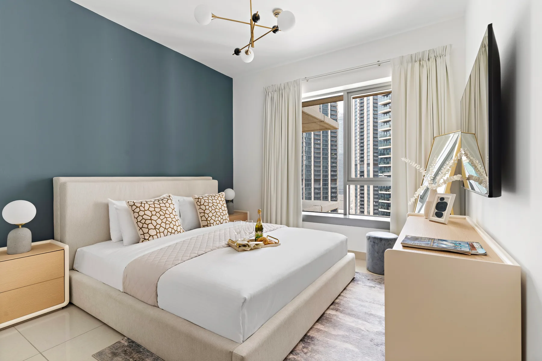 Un dormitorio luminoso con una cama bien arreglada y ventanas grandes.