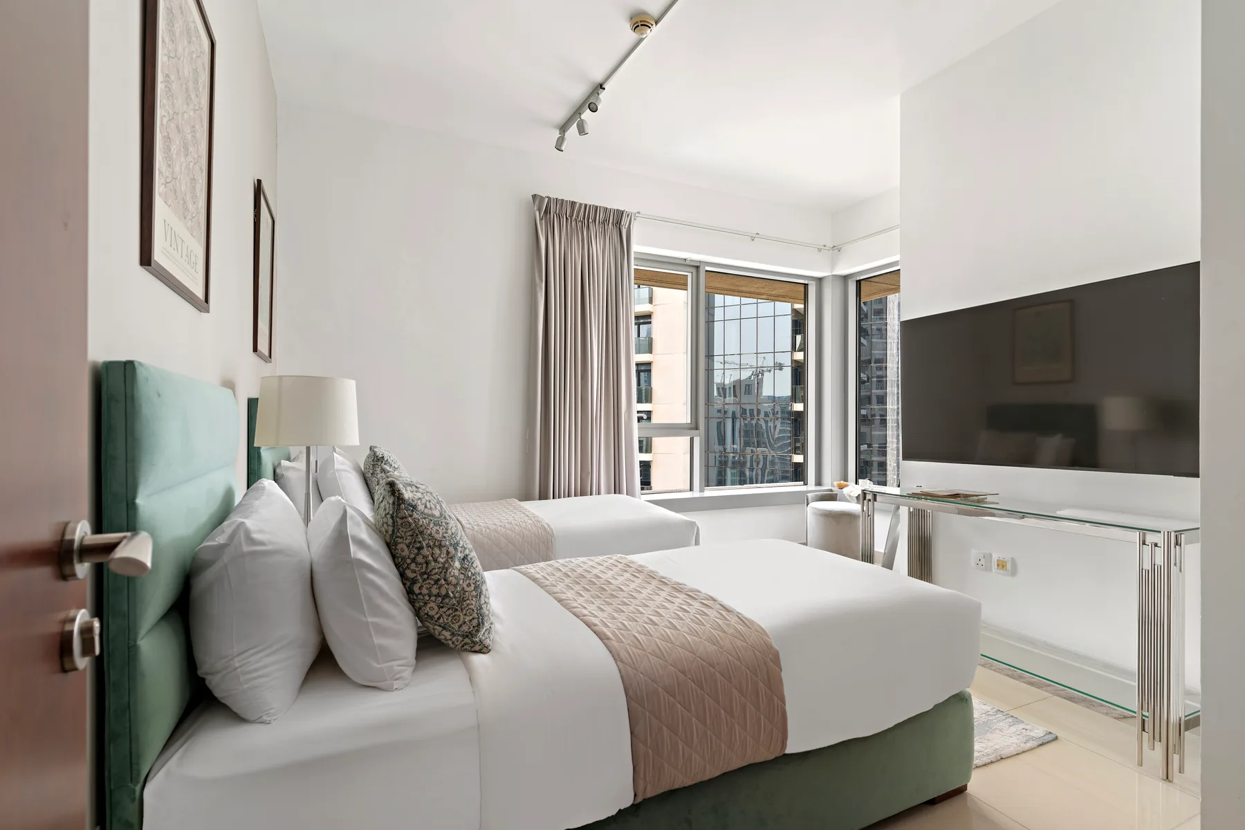 Un dormitorio luminoso con una cama bien tendida junto a grandes ventanas.