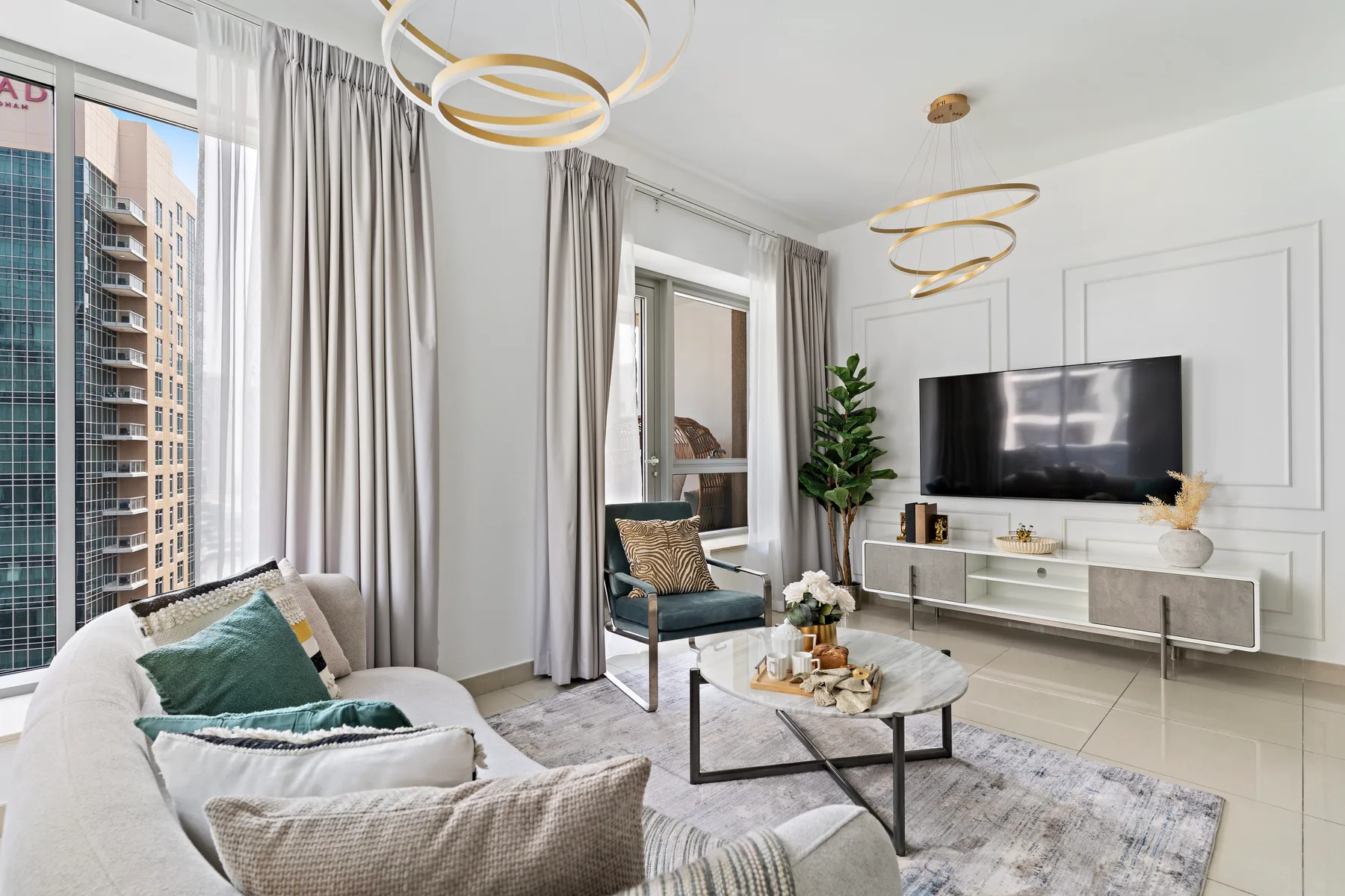 Una sala luminosa con asientos, un televisor y grandes ventanas.
