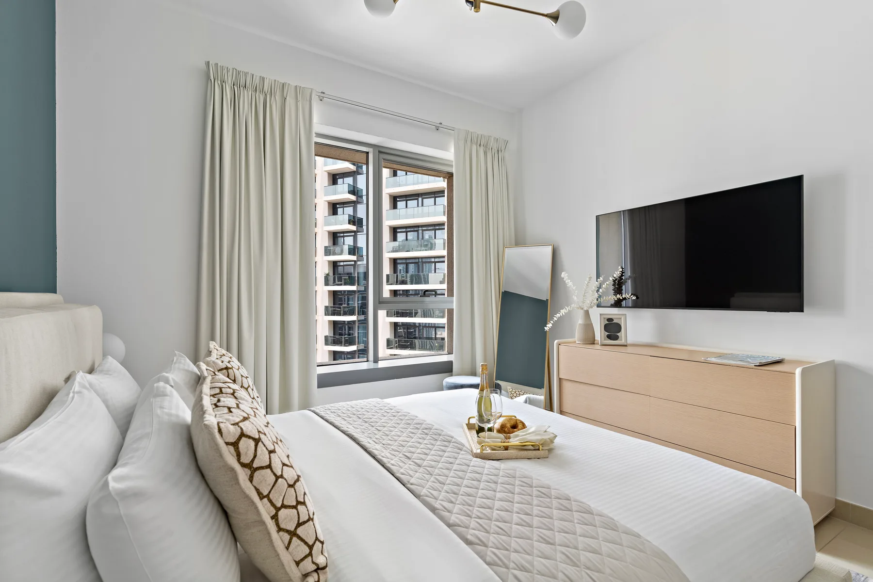 Un dormitorio luminoso con una cama bien arreglada y una ventana grande.