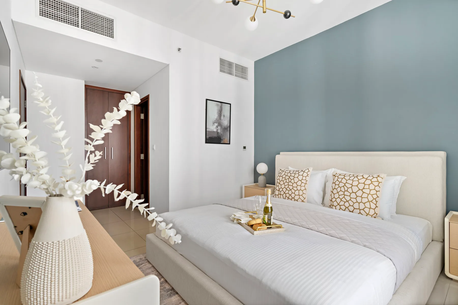 Un dormitorio luminoso con una cama grande, cojines estampados y una mesita de noche.