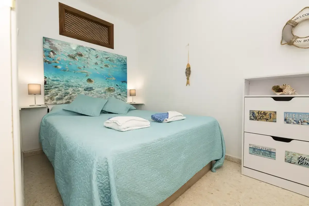 A bedroom with a bed covered in turquoise bedding.