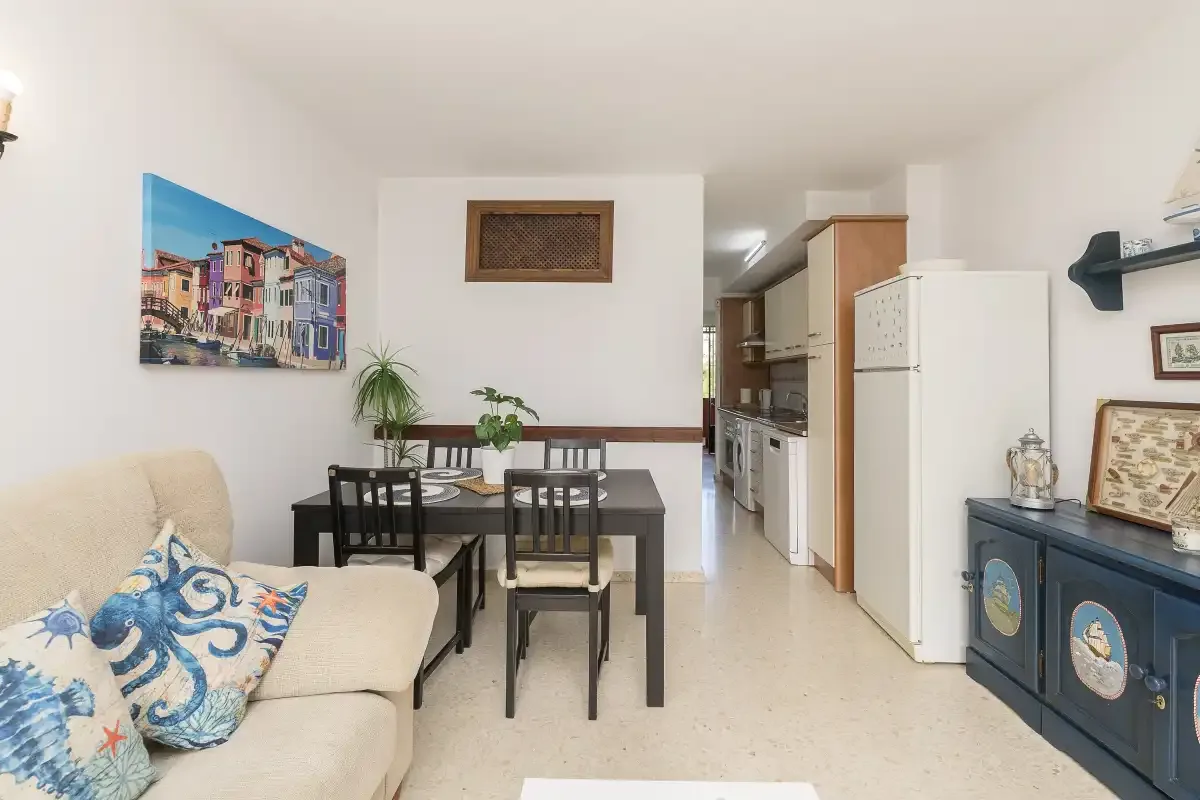 A dining area with a table and chairs sits beside a compact kitchen.