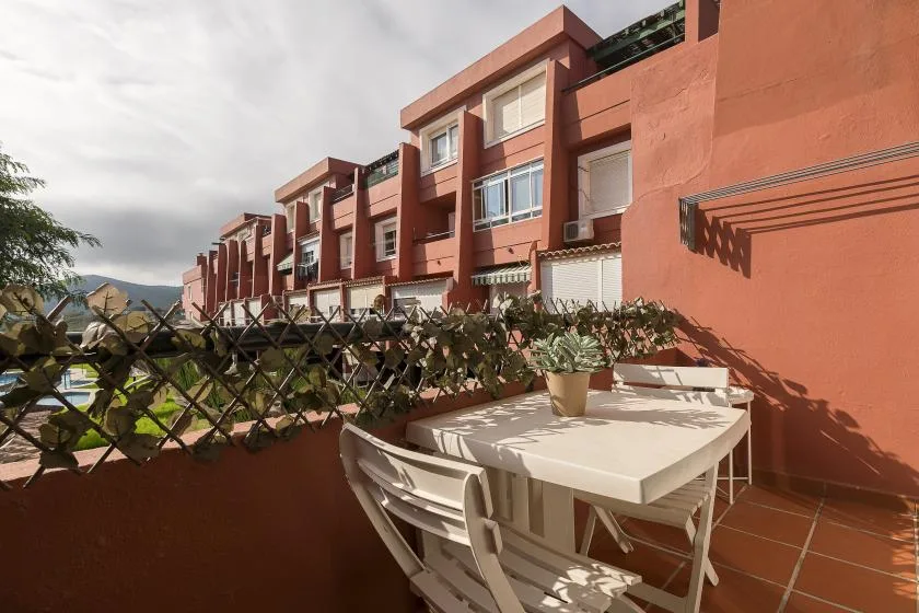 A terrace with outdoor seating overlooks a row of red apartment buildings.