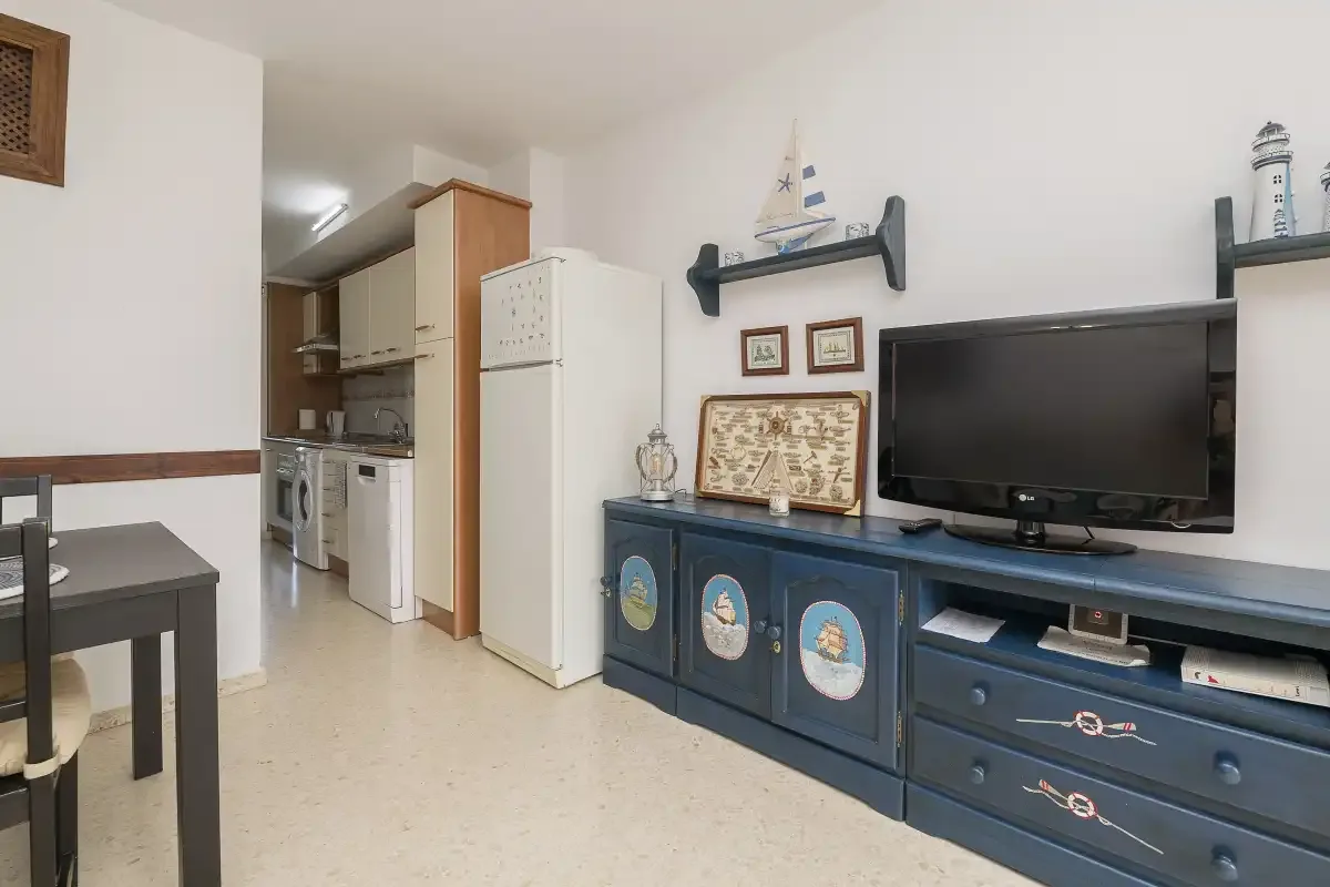 A living area with a television and a kitchenette in the background.