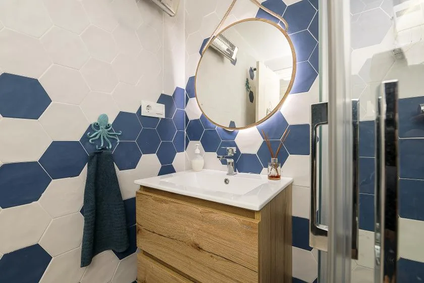 A bathroom vanity with a round mirror and blue-and-white tiled walls.
