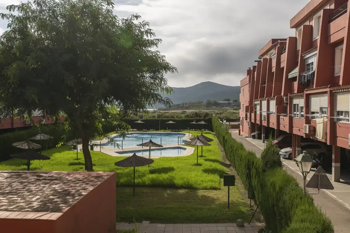 A landscaped courtyard with a swimming pool beside a row of red buildings.