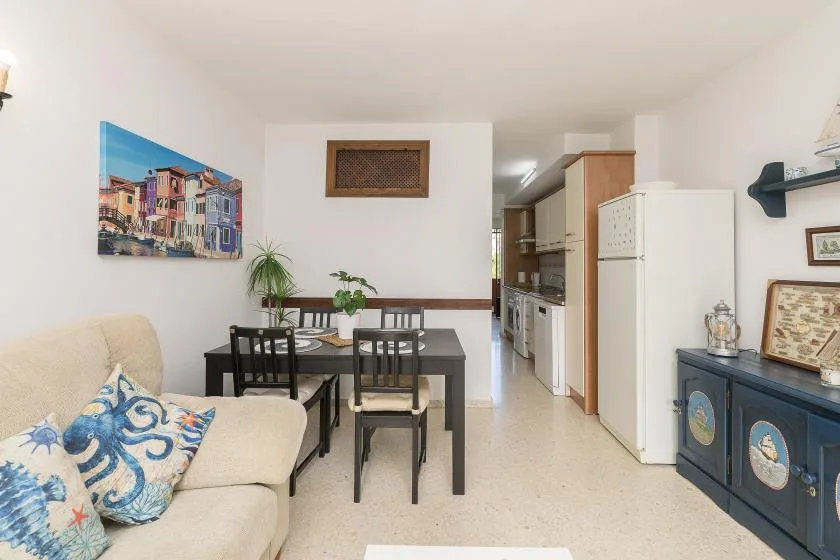 A living and dining area opens into a compact kitchen, with a table and seating.