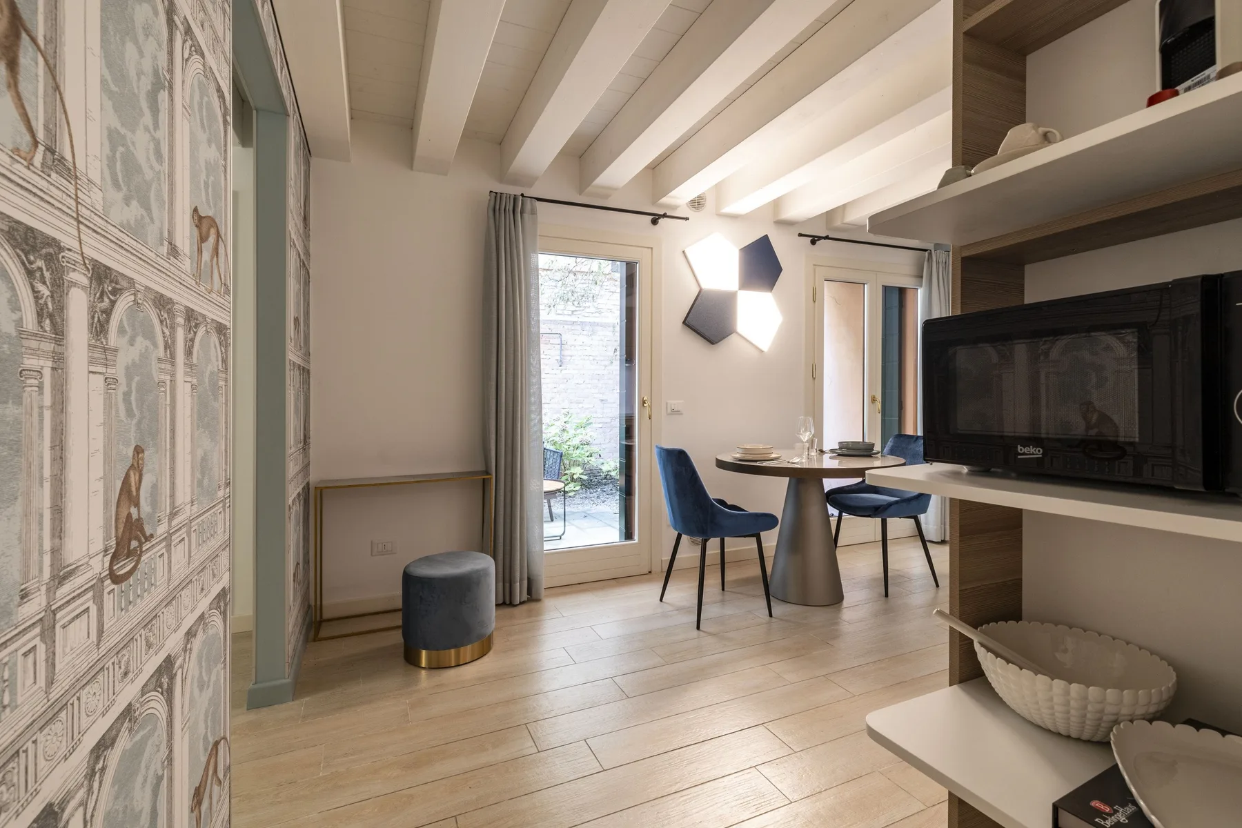 Zona de comedor y estar con una mesa, asientos y puertas de vidrio que dan a un patio.