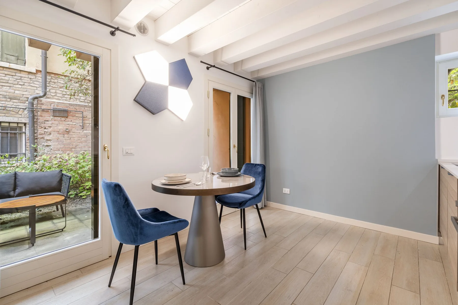 Un comedor con una mesa redonda y asientos azules junto a puertas de cristal.