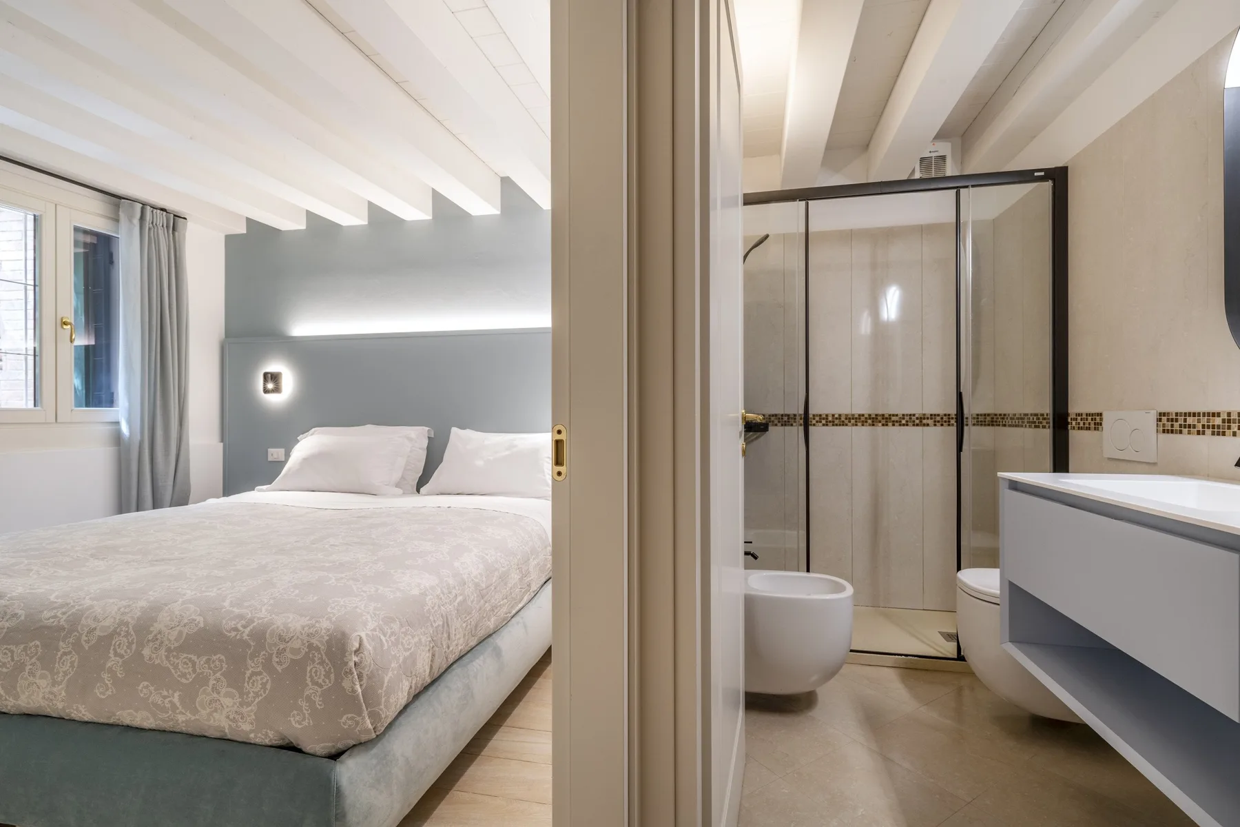 Se ve un dormitorio con cama junto a un baño contiguo con ducha.