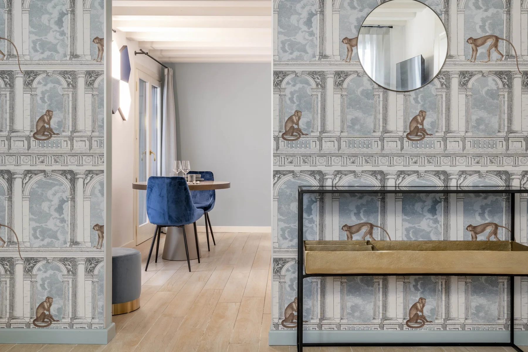 Un rincón de comedor con asientos azules está junto a una pared con papel pintado de animales.