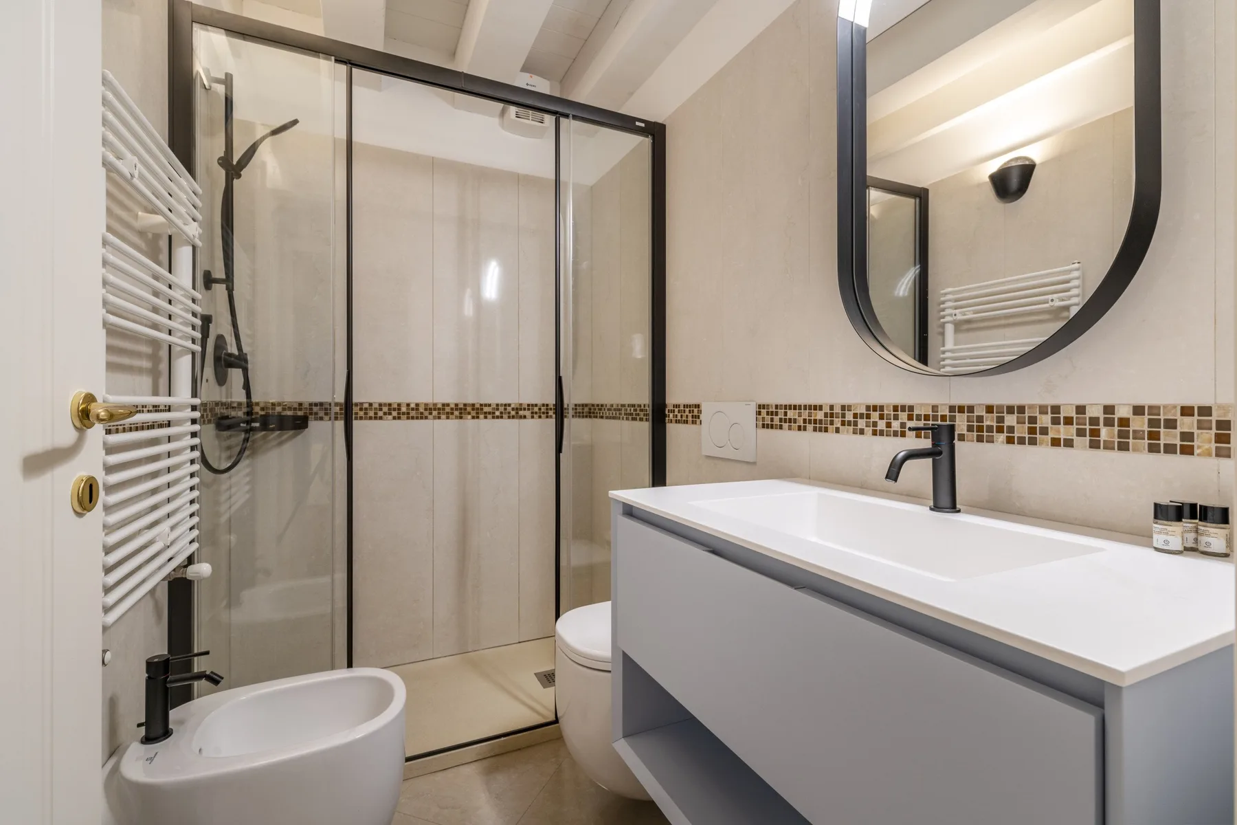 Un baño moderno con ducha de vidrio, bidé y un lavabo alargado.