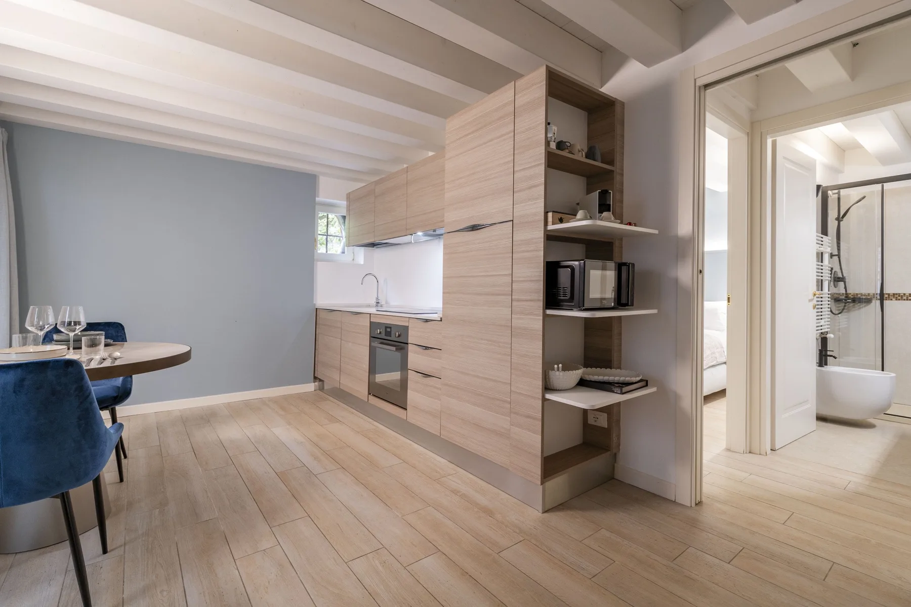 Una cocina y comedor modernos con gabinetes de madera clara y una mesa.
