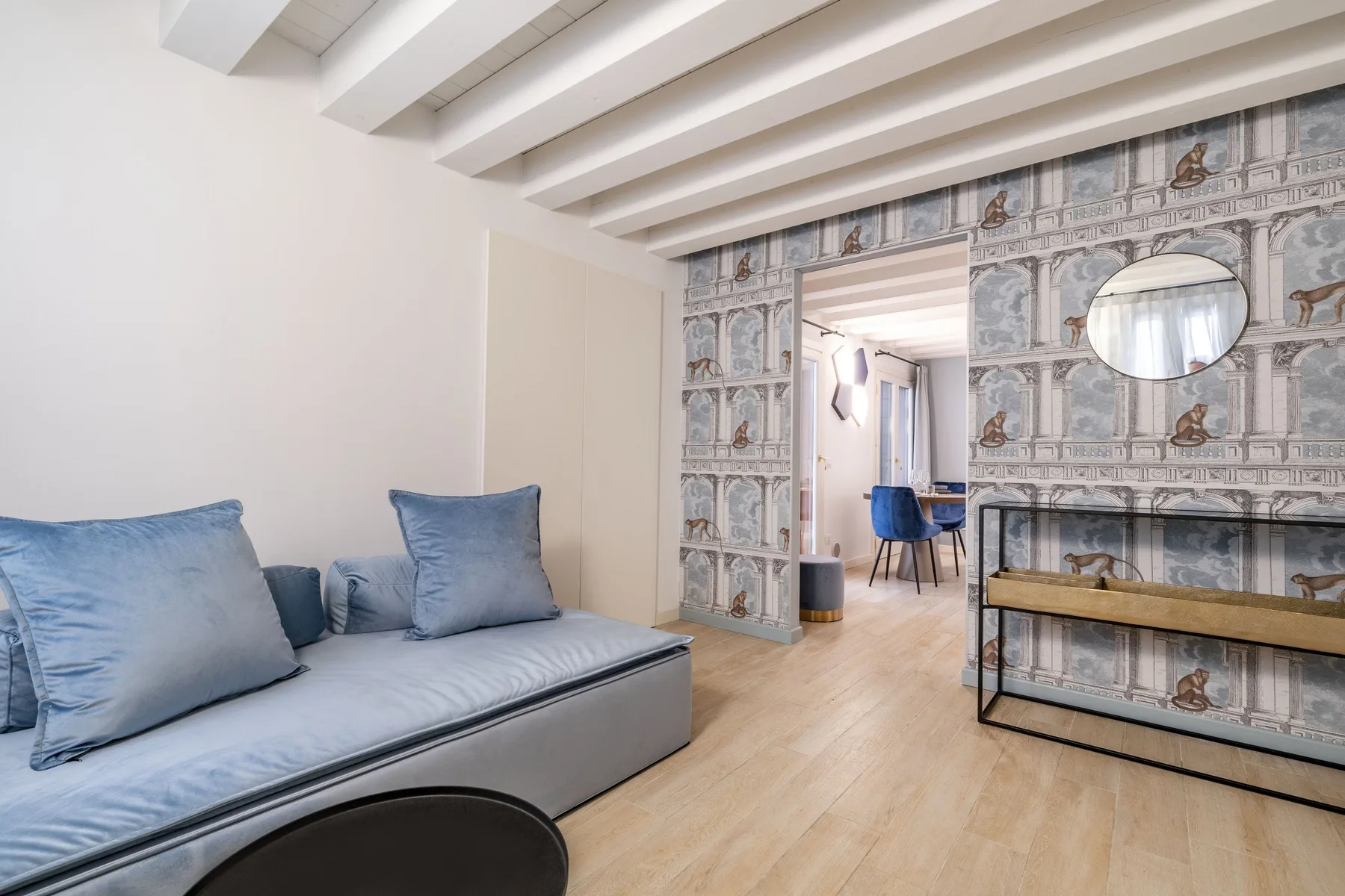 Una sala de estar con asientos azules y una pared estampada alrededor de una puerta abierta.