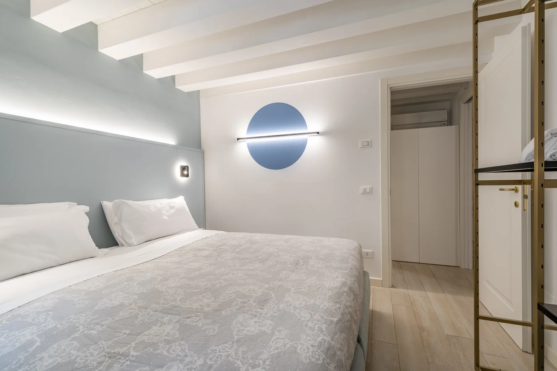 Un dormitorio con una cama bajo una lámpara de pared redonda.