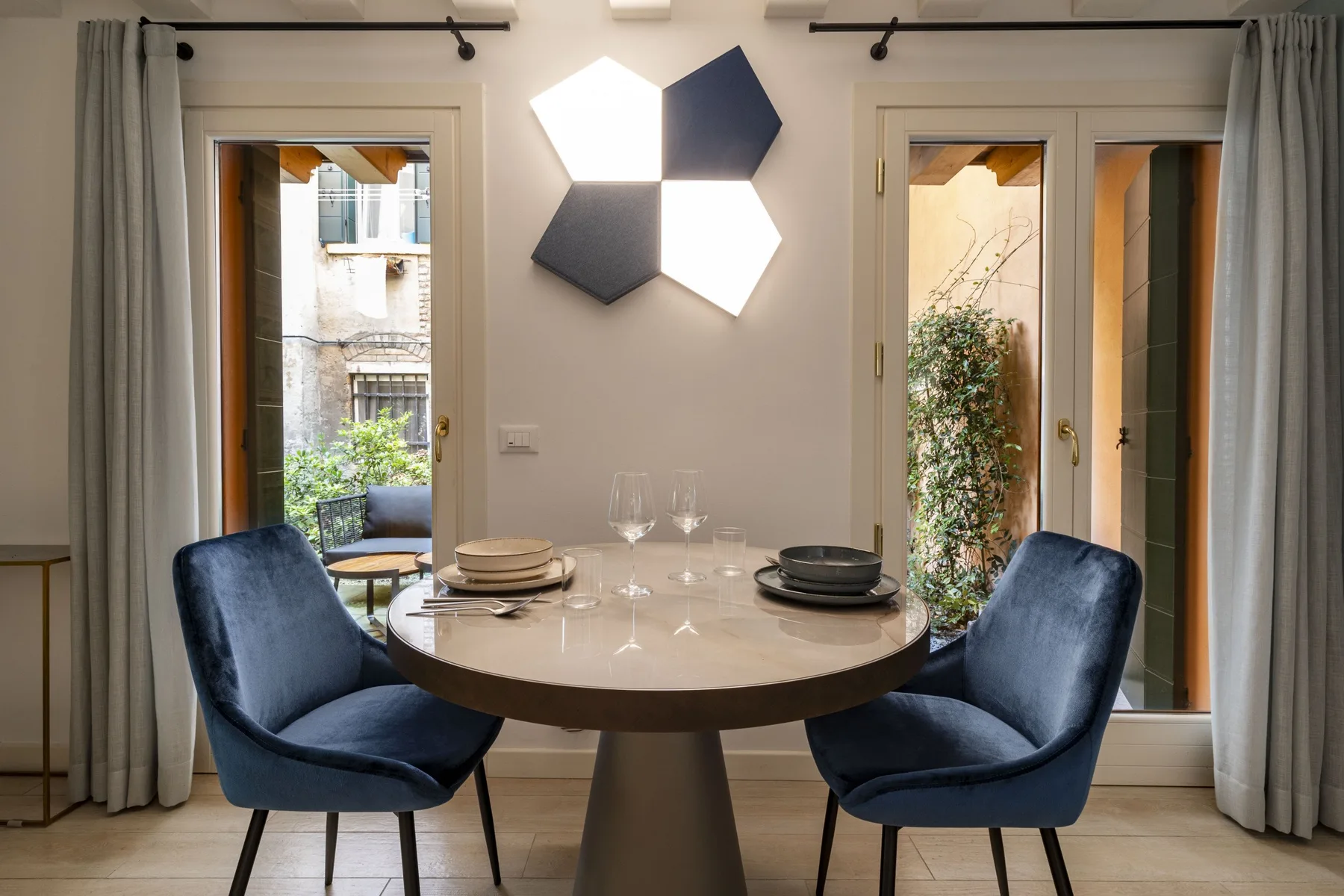 Un comedor con una mesa redonda entre dos asientos tapizados azules.