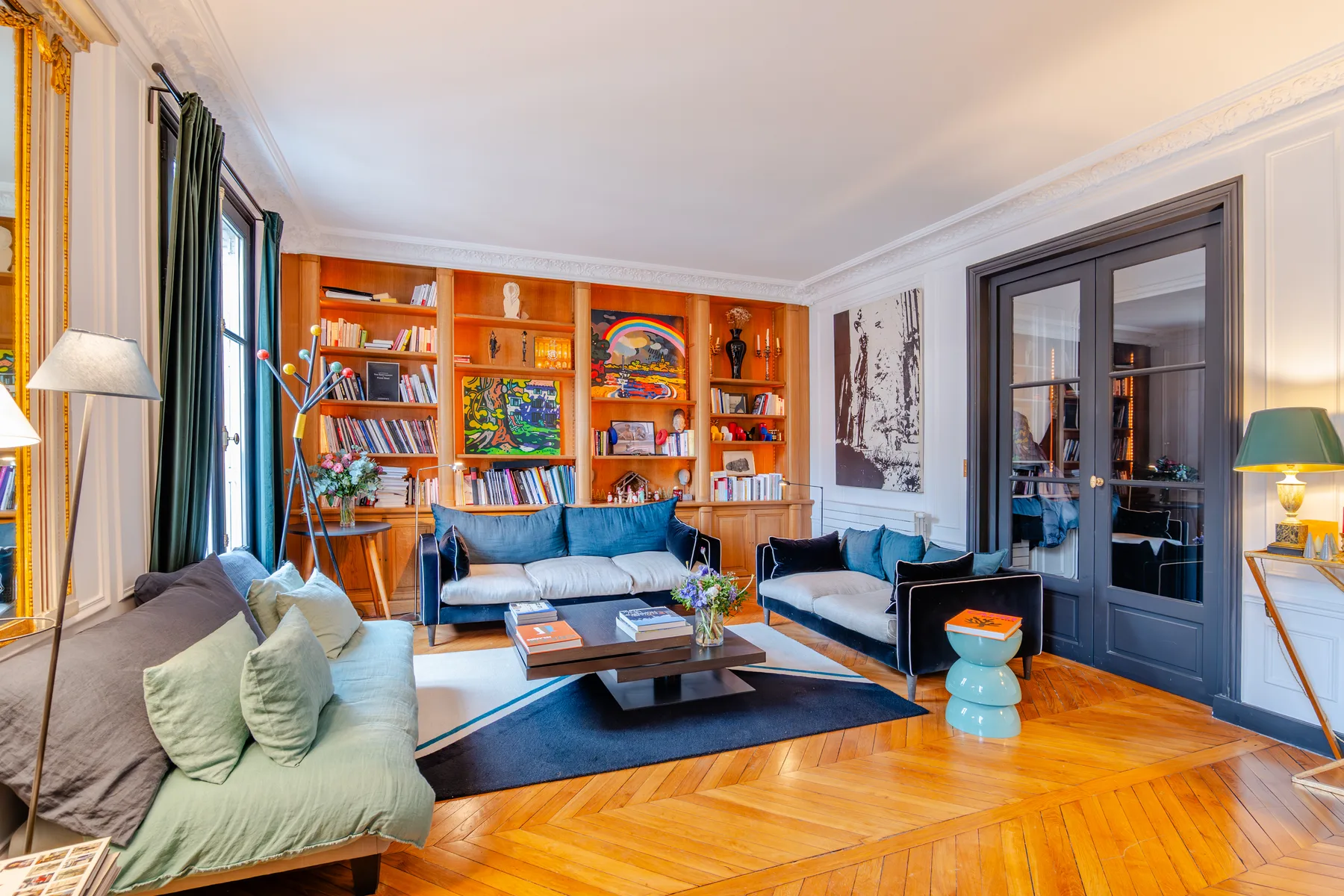 Living room with seating around a coffee table and a wall of bookshelves.