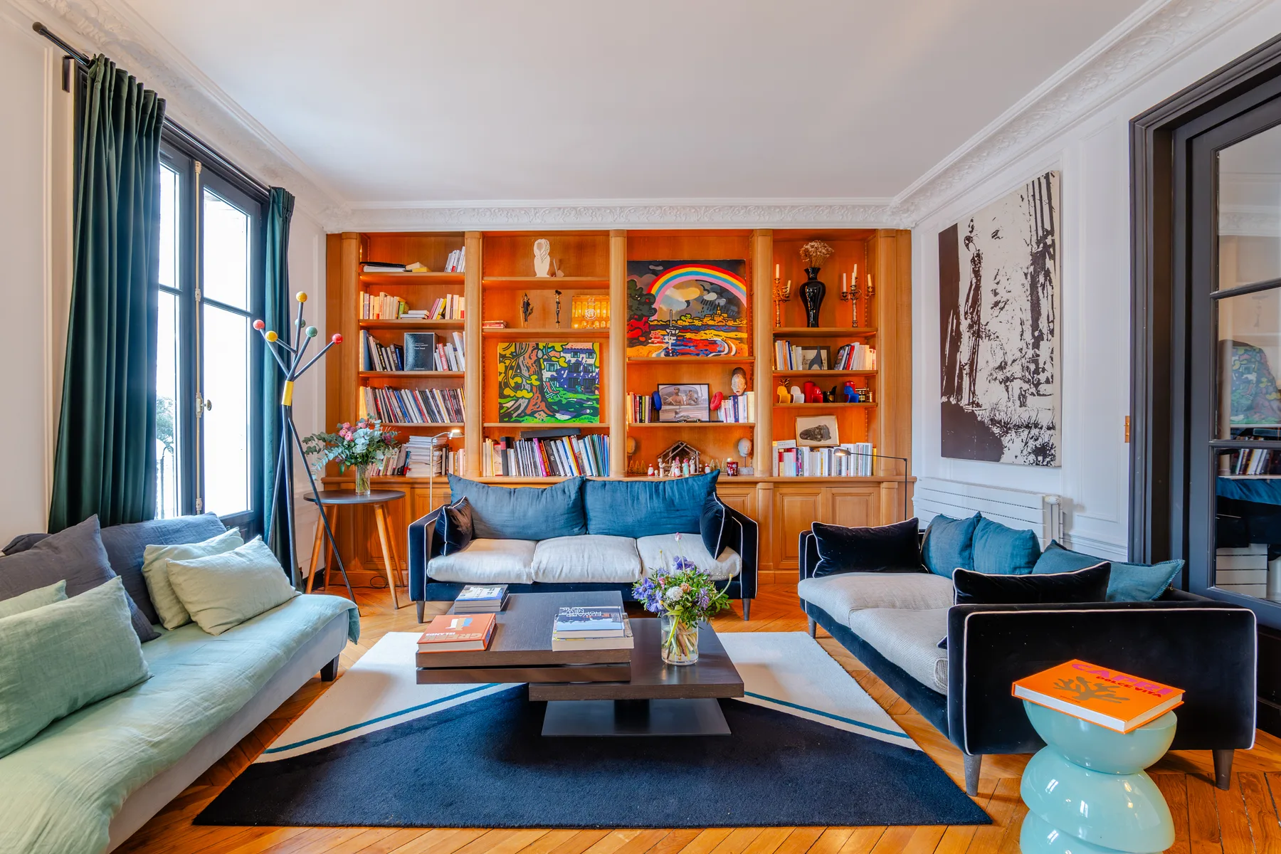 A living room with seating arranged around a coffee table and colorful bookshelves.