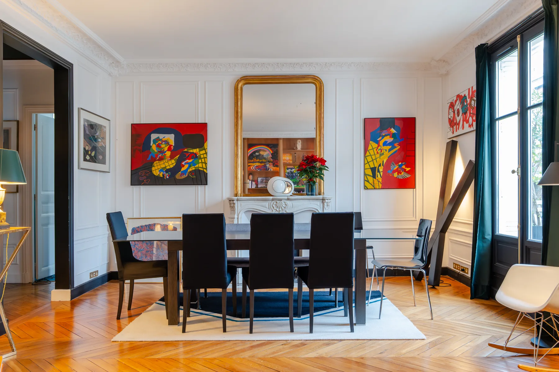 A dining room with a long table, dark seating, and colorful wall art.