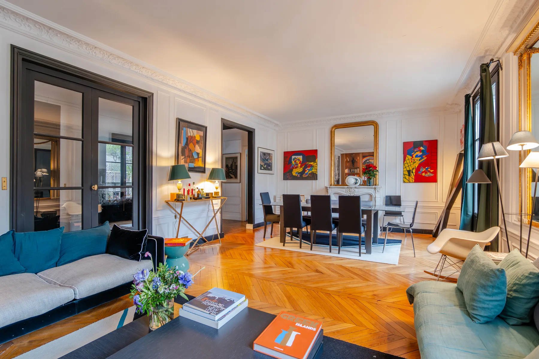 A living room with seating, a dining table, and colorful artwork.