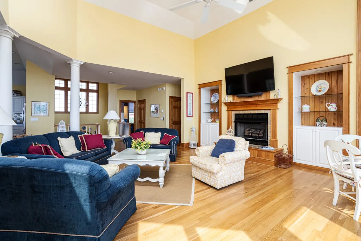 Una sala luminosa con asientos azules, una chimenea y un televisor.