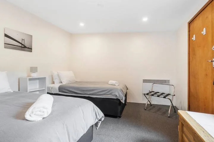 Un dormitorio con dos camas, toallas dobladas y un portaequipajes.