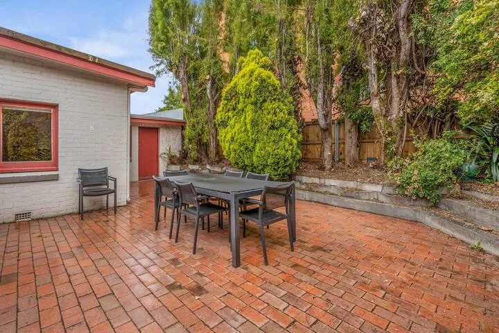 Una zona de comedor al aire libre con mesa y sillas en un patio de ladrillo.