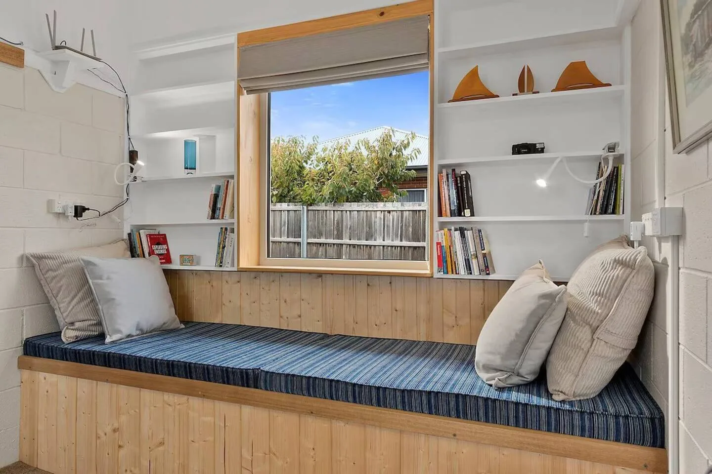 Un rincón de asientos junto a la ventana, con cojines y estantes empotrados.