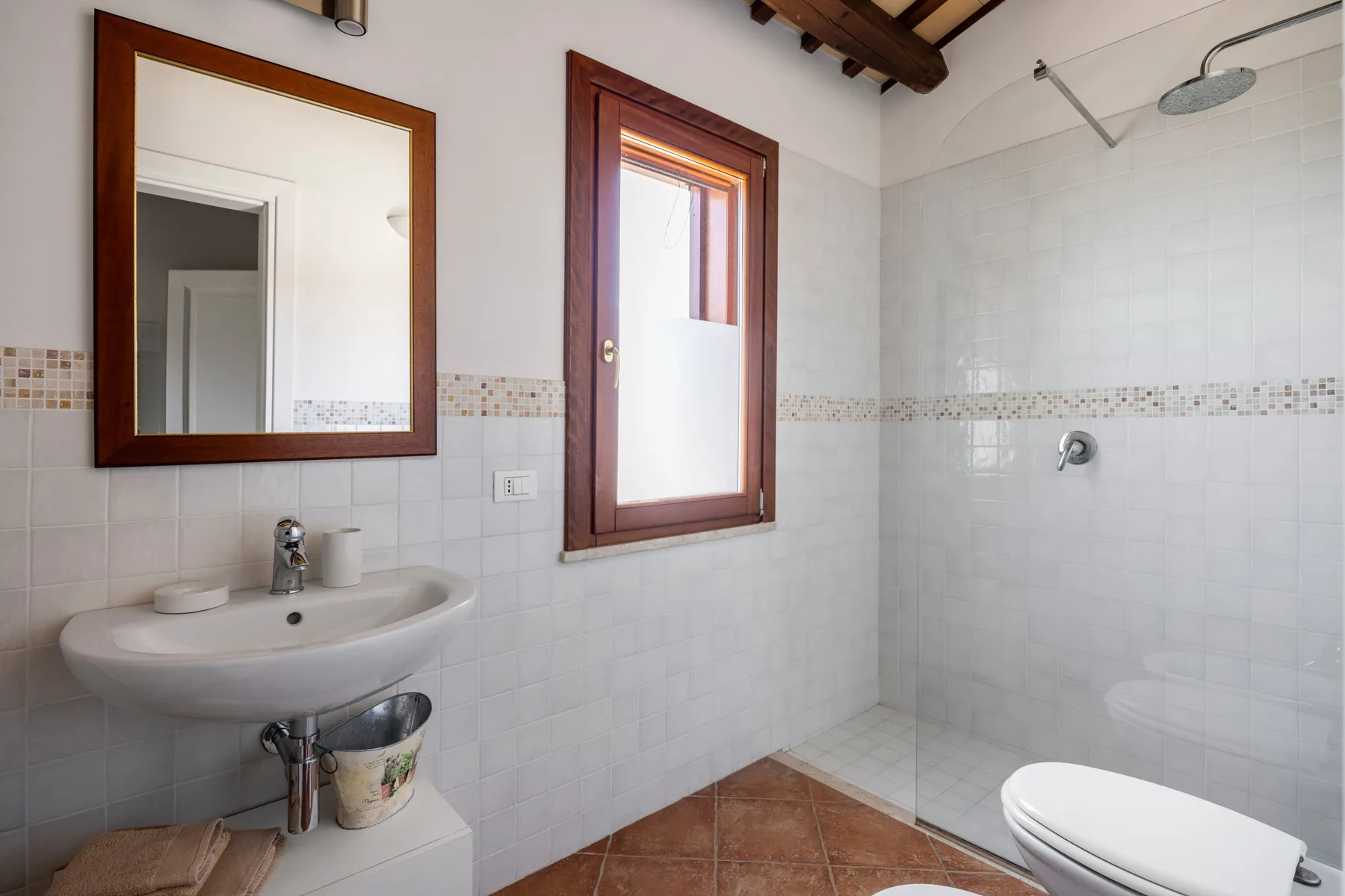 A tiled bathroom with a wall-mounted sink and glass shower area.