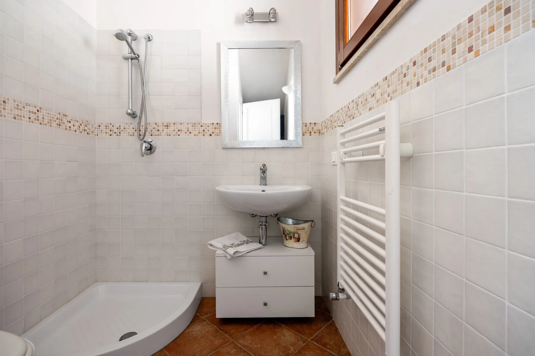 A tiled bathroom with a shower, sink, and wall mirror.