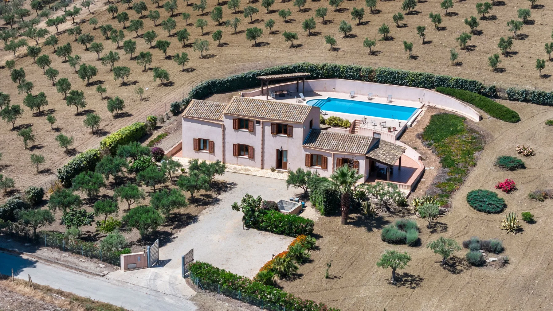 Aerial view of a country house with a swimming pool amid planted fields.