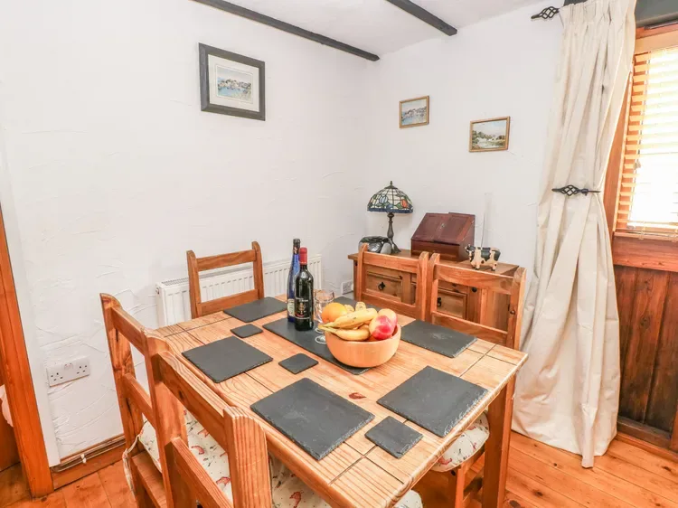 Una mesa de comedor de madera con puestos preparados está en un comedor luminoso.