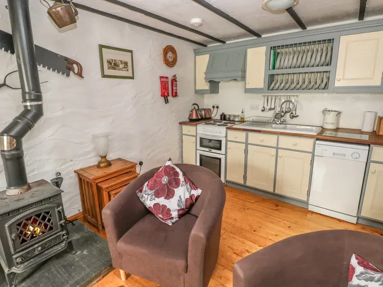 Una cocina rústica con una estufa de leña y un sillón con cojín.