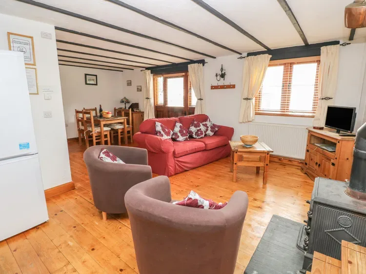 Una sala de estar con un sofá rojo, dos sillones y una mesa de centro de madera.