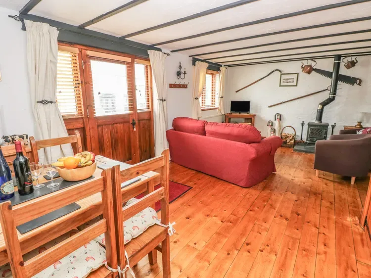 Una sala de estar con asientos rojos, suelo de madera y una mesa de comedor.