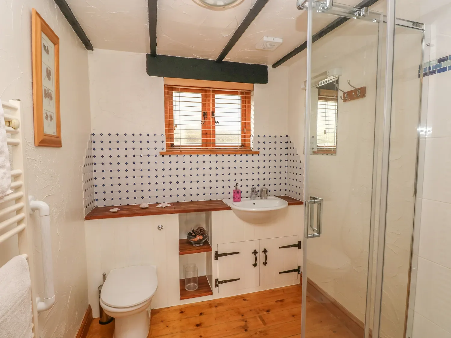 Un baño con inodoro, lavabo, ducha y suelo de madera en Cowslip Cottage, en Rosemarket.